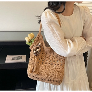 Détail du sac cabas bohème tissé main avec perles en bois et pompons décoratifs élégants