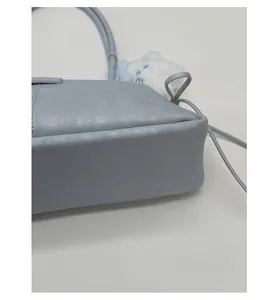 Detail view of reinforced flat base and light blue textured leather of the handbag