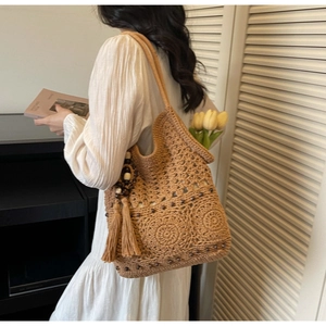 Détail d'un sac cabas bohème en paille avec des franges et perles en bois