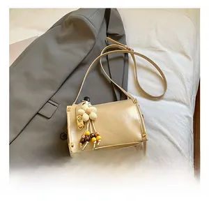 Close-up of beige leather handbag with floral charm and gold metal rivet details
