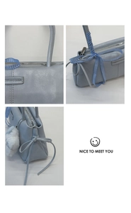 Detail view of light blue retro handbag with plush charm and fashion brand label