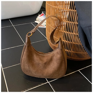Detail of vintage brown suede hobo bag with gold hardware on a modern tiled background