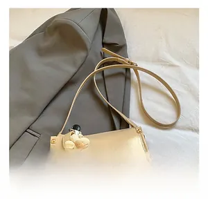 Close-up of beige leather crossbody bag with adjustable strap and floral charm detail