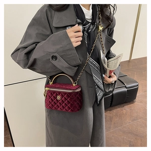 Detail of burgundy velvet quilted crossbody bag with gold handle and clover logo