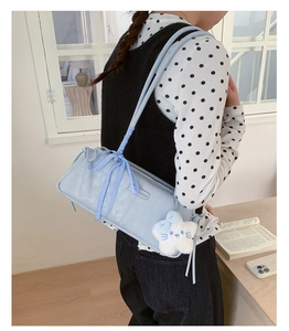 Detail of light blue Boston bag with ribbon bow strap and star plush pendant