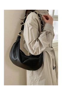 Détail du sac lune en cuir noir avec grosse chaîne dorée et détails plissés élégants