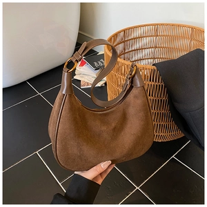 Detail of dark brown hobo bag with suede texture and gold hardware ring on strap
