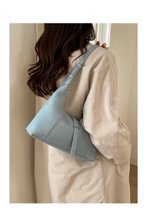 Dettaglio di una borsa hobo azzurra che mostra il design asimmetrico e la pelle opaca