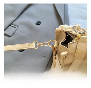 Detailed view of glossy gold metal hooks and connectors on a cream leather shoulder bag