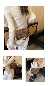 Detail of coffee brown woven crossbody bag with gold logo and plush doll charm