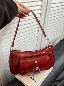 Stylish red underarm bag in glossy faux leather with decorative silver metal buckles