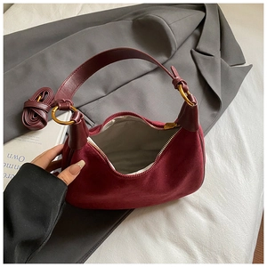Detail of burgundy suede crescent bag with gold zipper and detachable shoulder strap