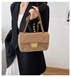 Détail d'un sac bandoulière en daim marron avec matelassage et chaîne dorée