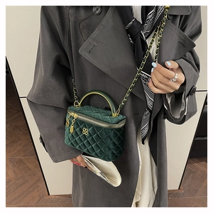 Detail of dark green velvet quilted vanity bag with golden handle and clover clasp