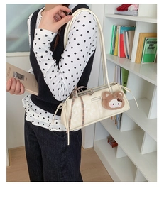 Detail of cream vintage baguette bag with bear pendant and plaid bow on model