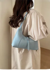 Modella che indossa una borsa hobo azzurra con un cappotto beige per un look di classe