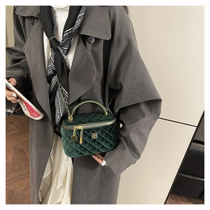 Detail of dark green velvet quilted bag with clover logo and gold chain strap