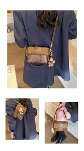 Detail view of brown woven texture handbag with gold chain strap and plush charm