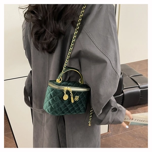 Close-up of dark green velvet quilted bag with gold chain strap and metal handle detail