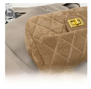 Gros plan d'un sac à bandoulière en daim matelassé marron avec fermoir tournant doré