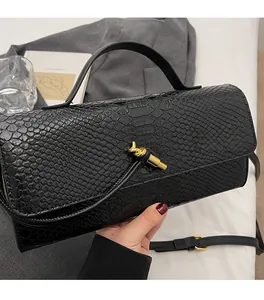 Detail der schwarzen Baguette-Tasche mit Schlangenmuster, Goldverschluss und Schultergurt