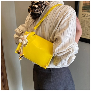 Close-up of bright yellow patent leather crossbody bag with decorative 3D floral charm