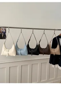 Cinque borse hobo vintage in vari colori appese a una rastrelliera metallica