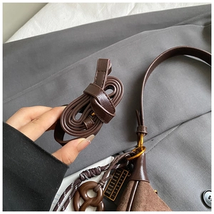 Detail of retro brown crossbody bag featuring matte suede texture and golden abacus charm