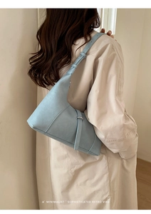 Dettaglio di una borsa a tracolla in pelle azzurra minimalista con fibbia in metallo argento