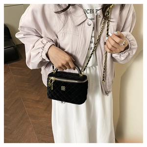 Black velvet quilted mini vanity bag with gold-tone hardware and chain strap shown on model