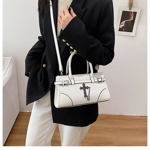 Detailed view of white woven handbag with vintage metal cross pendant and detachable strap