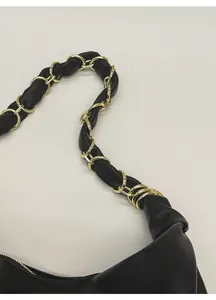 Détail de la bandoulière en cuir noir avec maillons de chaîne dorés et coutures