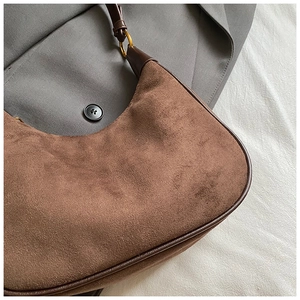 Detail of vintage dark brown suede hobo bag with bronze hardware and smooth leather trim