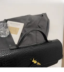 Nahaufnahme der schwarzen Schlangenprägung der Handtasche mit goldenem Drehverschluss