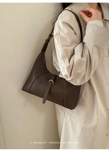 Borsa sottobraccio in pelle opaca marrone scuro abbinata a un trench beige elegante