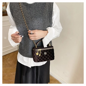 Detail view of burgundy velvet quilted bag with gold clover logo and chain strap