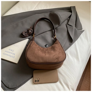 Detail of vintage brown suede crescent shoulder bag with leather trim and gold hardware