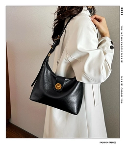 Detail of black leather hobo bag with gold metal buckle and adjustable strap