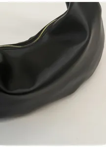 Détail du grain de cuir noir souple et de la courbe en croissant du grand sac à main
