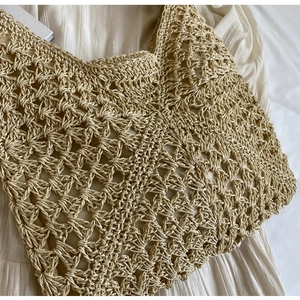 Detailed close-up of handmade woven straw bag with hollow crochet geometric pattern