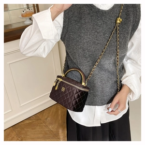 Detail of dark brown quilted mini bag featuring golden floral logo and chain strap