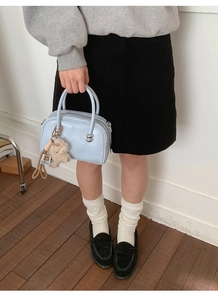 Détail du sac à main bleu clair avec breloque mouton en peluche et doubles poignées
