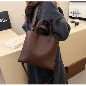 Side view of brown litchi pattern leather tote bag worn by model in a cozy cafe setting