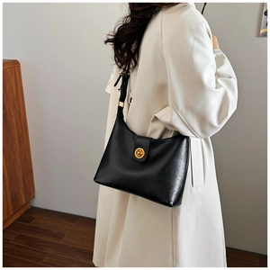 Side view of elegant black leather shoulder bag with gold metal clasp on model