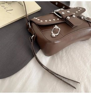Macro shot of dark brown retro shoulder bag with silver rivets and metal buckle details
