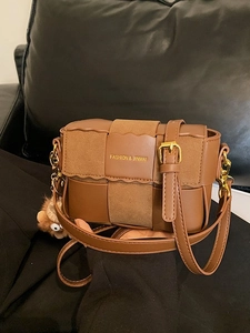 Brown woven crossbody bag with plush bear charm and adjustable leather shoulder strap