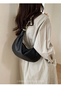 Sac hobo noir chic avec bandoulière chaîne dorée porté par un mannequin sous une lumière douce