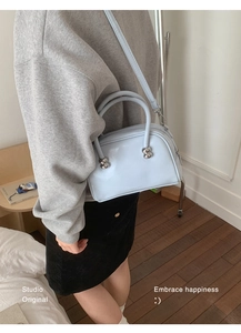 Sac baguette en cuir verni bleu clair brillant avec détails argentés porté à l'épaule