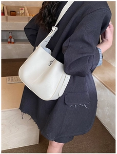 Detailed view of cream leather bucket bag with silver buckle and wide strap on model