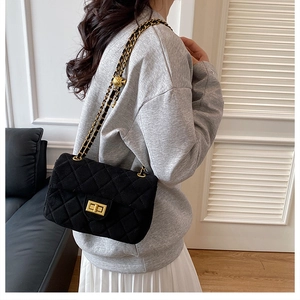 Détail du sac bandoulière en velours noir matelassé avec chaîne dorée et réglage